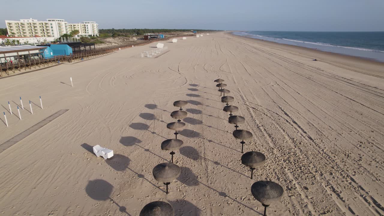 avión no tripulado volando hacia atrás sobre la playa de montegordo, sombreros de sol de la estación de playa, algarve