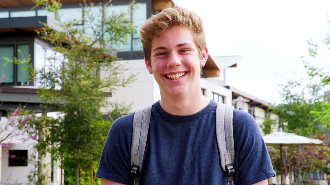 retrato de un estudiante de secundaria masculino fuera de los edificios de la universidad filmado en cámara lenta
