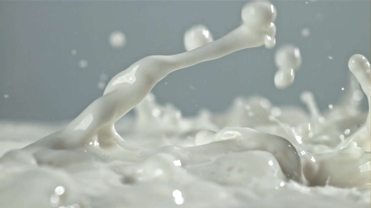 白い牛乳が飛び散り、しずくが形成されるクローズアップのスローモーション。
