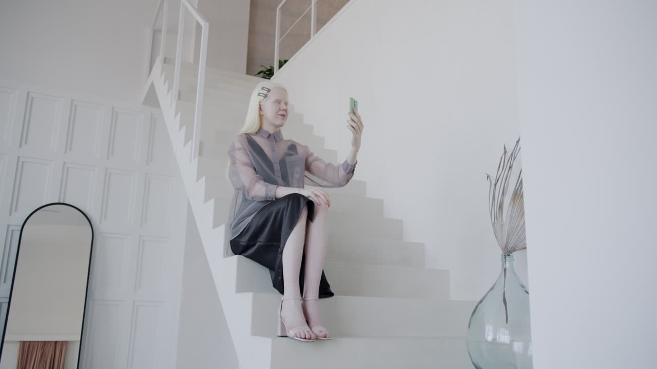Woman taking a selfie on stairs in a modern home