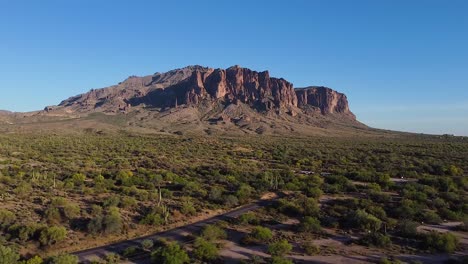 desert road with cactuses leading to superstition mountains during sunset in arizona