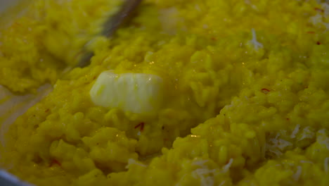 Mezclando-Cremoso-Risotto-De-Azafrán-Amarillo-Con-Una-Nuez-De-Mantequilla-Derretida-En-El-Centro