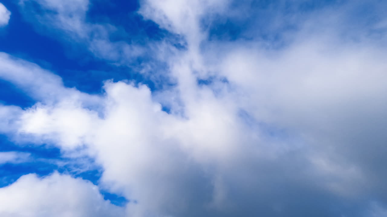 Thick white clouds spreading in the sky. Quickly flying cloudscape covering the azure sky. Timelapse.