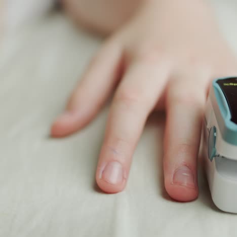 child's hand with a heart rate monitor on finger measures pulse and blood oxygen saturation 2