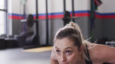 Close-up-video-of-determined-caucasian-woman-doing-push-ups-working-out-at-a-gym