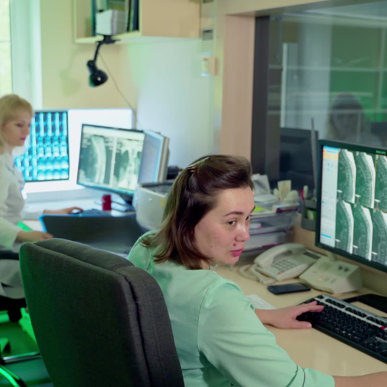 Professionals working in the control room of MRI examination. Female doctors sitting in front of computers and discussing the case