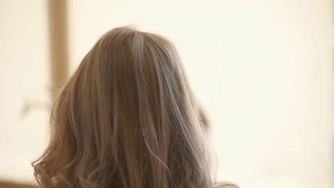 mujer ajustando su cabello rubio rizado