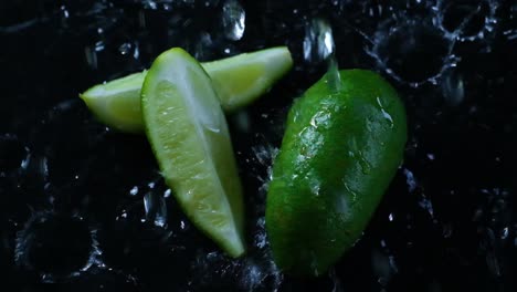 Wassertropfen-Fallen-Auf-Kalkscheiben-Auf-Einer-Schwarzen,-Nassen-Oberfläche