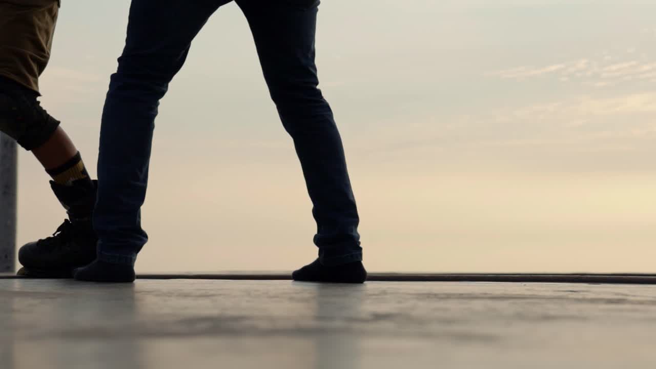Silhouette di giovane pattinatore e ciclista al tramonto