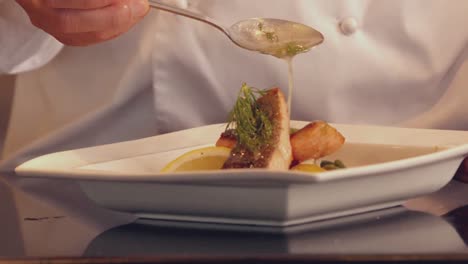 chef pouring sauce over fish dish