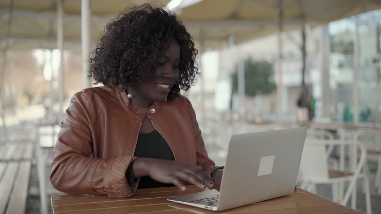 Focused young woman working with laptop in cafe