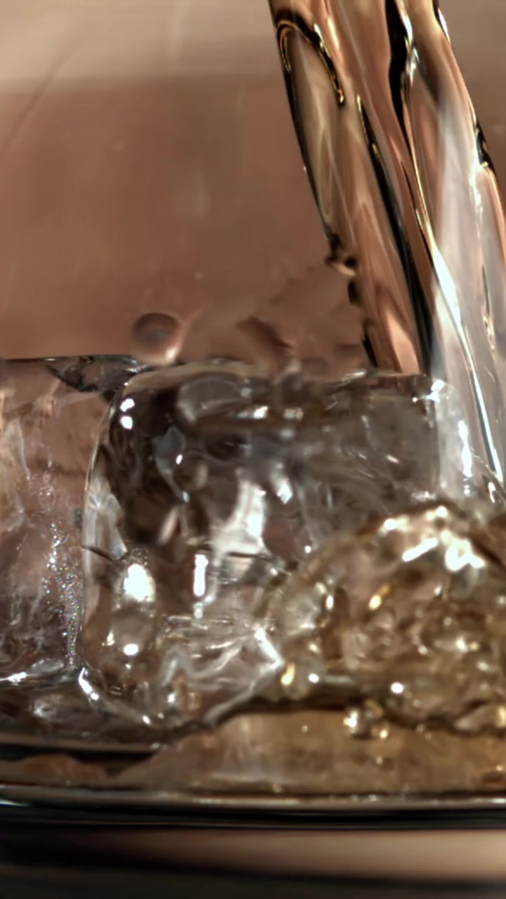 Primo piano di liquido che si versa su cubetti di ghiaccio in un bicchiere