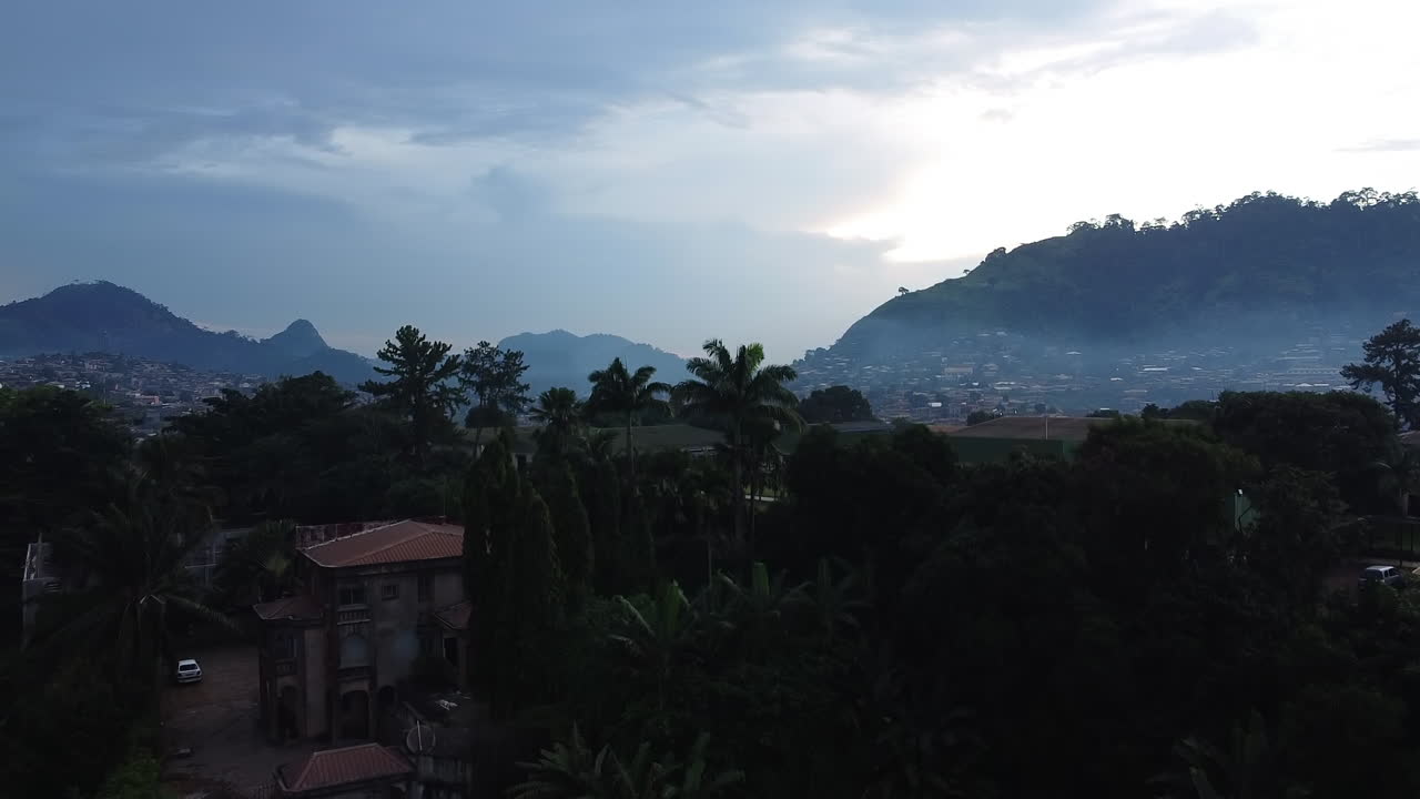 Vista aerea che si innalza sopra gli alberi, rivelando il paesaggio urbano di Etoug-Ebe, avvolta nella foschia, a Yaoundé, Camerun.