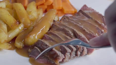 cierre el control deslizante de cámara lenta de comer bistec y papas fritas con un tenedor