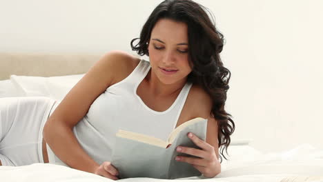 una mujer de cabello moreno lee un libro.