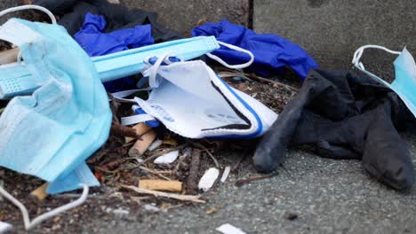 dirty disposable corona virus polluted face masks and latex gloves among cigarette rubbish on street curb dolly left