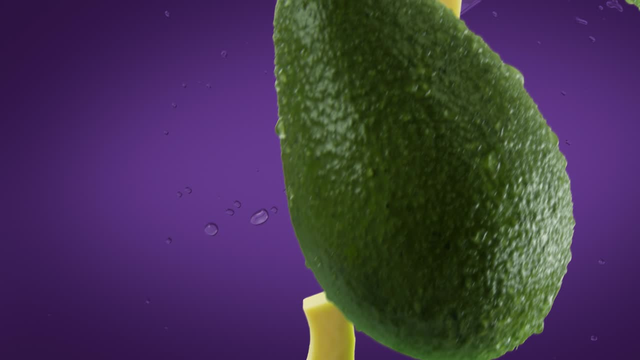 aguacate con rebanadas y salpicaduras cayendo sobre un fondo púrpura