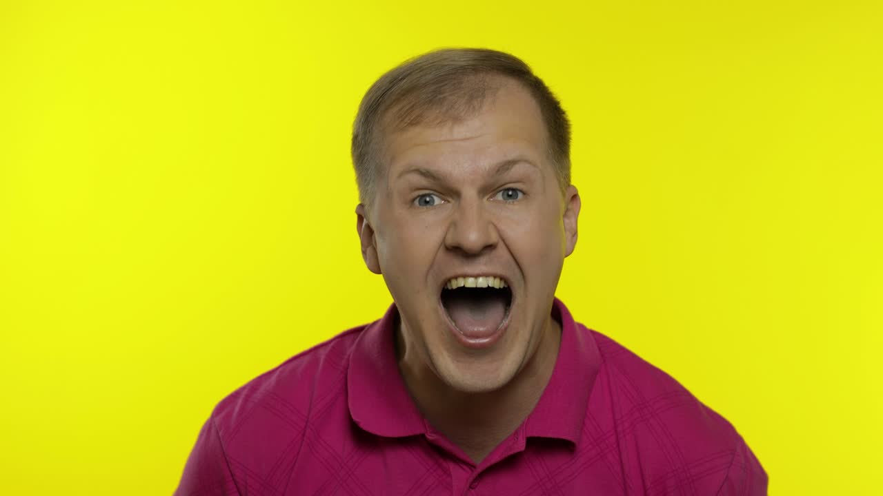 retrato de un joven posando en una camiseta rosa. un chico guapo feliz riendo en voz alta, mirando a la cámara