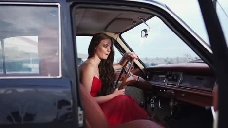 woman in a red dress driving a vintage car
