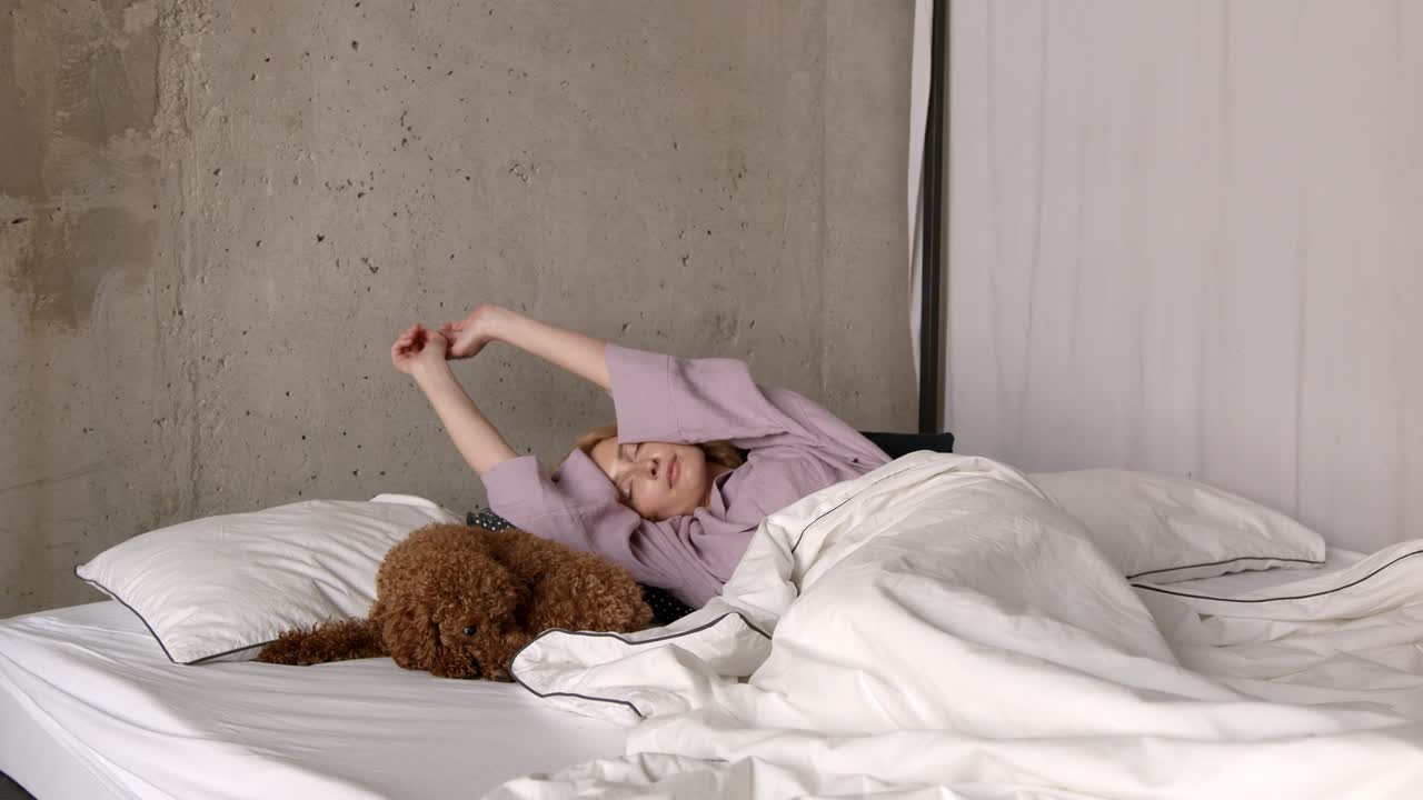 mujer joven despertando en la cama con el perro