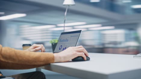 360 degree modern office: caucasian businessman sitting at his desk working on a laptop computer. man working with big data e-commerce analysis. energetic fast tracking shot. camera moving around