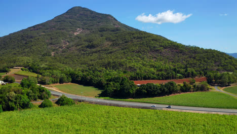 green fields and forest mountains with traveling cars at country road in cairns, qld australia