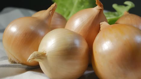 many large golden onion heads spinning against a background of green lettuce leaves. eco products. healthy food concept. 4k