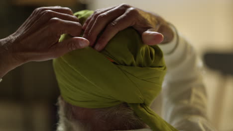 fotografía de estudio de cerca de un anciano sikh con barba atando tela para el turbante vista desde atrás tomada en tiempo real 2