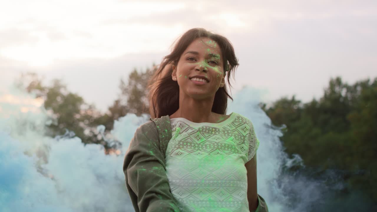 una mujer multirracial bailando con bombas de humo de colores en el festival de holi, filmada con una cámara de helio rojo en 8k.