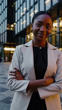 young african american businesswoman stands confidently with crossed arms, exuding professionalism and success in front of a modern office building