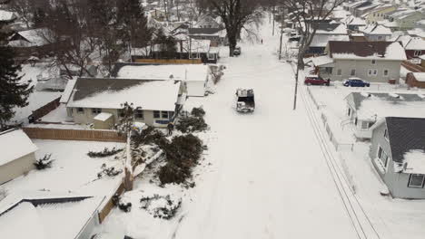 aerial view of safety team clearing fallen tree near the house in a residential neighborhood covered in snow