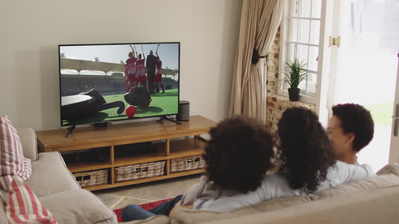 Famiglia felice seduta a casa insieme che guarda una partita di hockey in TV