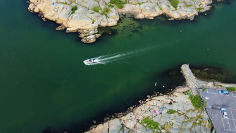 speedboat swiftly sailing on the turquoise blue sea in saltholmen peninsula, sweden - classic bathing spot in gothenburg - aerial drone, slow motion