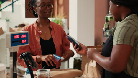 African-american-client-paying-for-bio-goods-at-checkout