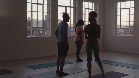 yoga class group of healthy people ready for early morning fitness workout chatting sharing lifestyle training practices in studio at sunrise
