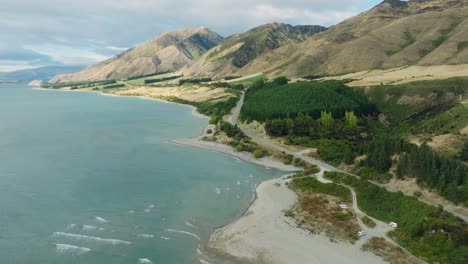 Hermosa-Vista-Aérea-De-La-Sinuosa-Carretera-Y-El-Lago-Hawea-En-La-Región-Montañosa-De-Otago-En-La-Isla-Sur-De-Nueva-Zelanda-Aotearoa