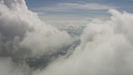 Aerial-dolly-shot-through-dense-white-clouds-revealing-a-snowy-landscape-below