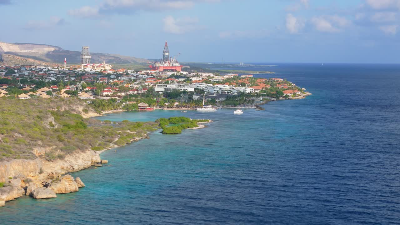 Aerial dolly along cliffs of the Jan Thiel coastline in Curacao, with rocky cliffs, turquoise waters, and clear skies