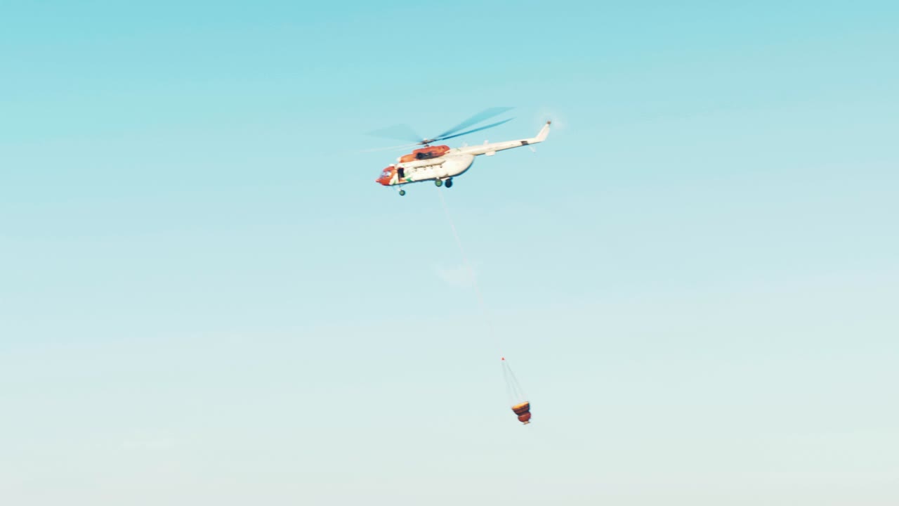 산불에 물통을 채운 후 날아가는 헬리콥터