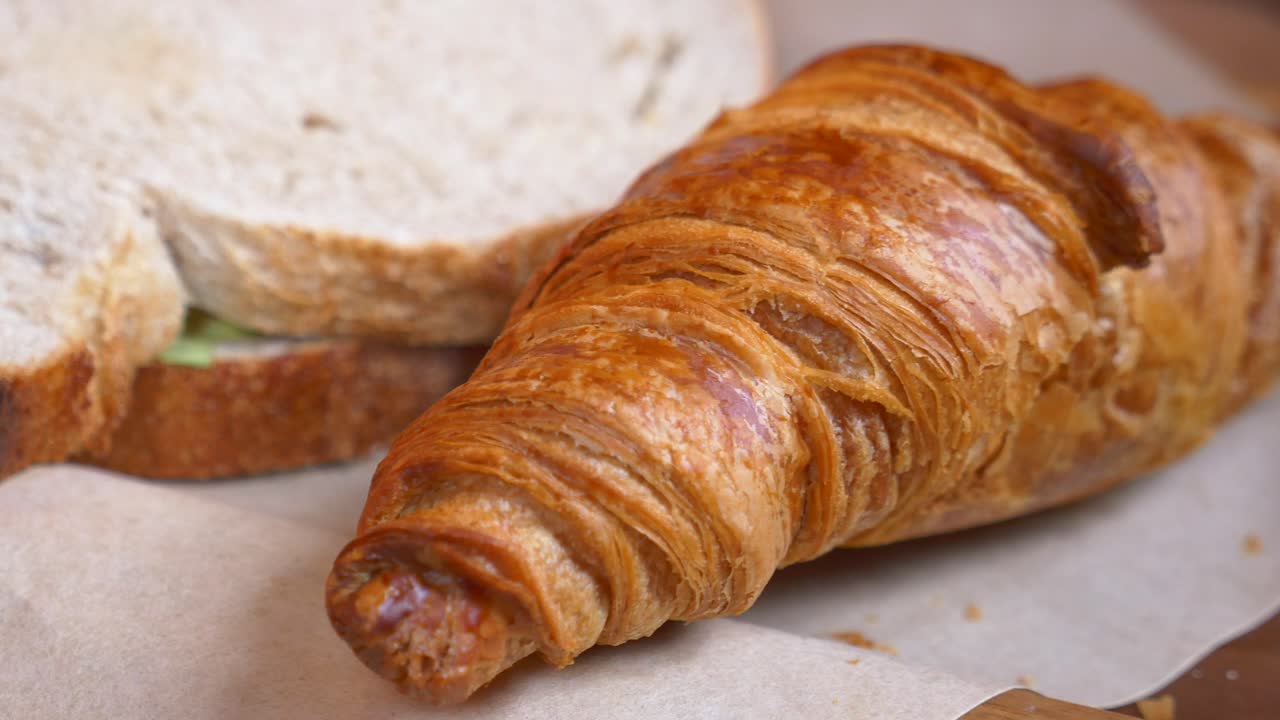 primer plano de un croissant de mantequilla y un sándwich de trigo