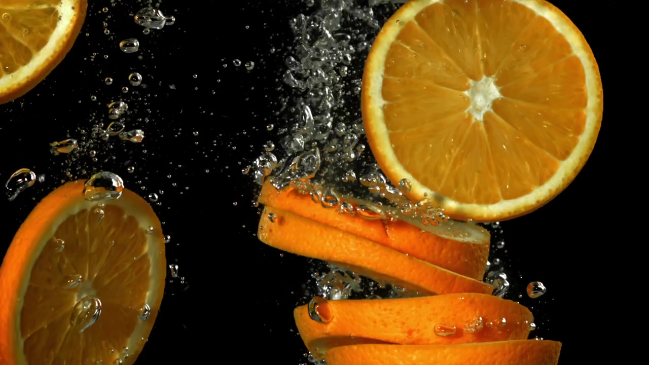 Fette d'arancia fresche che schizzano nell'acqua con bolle