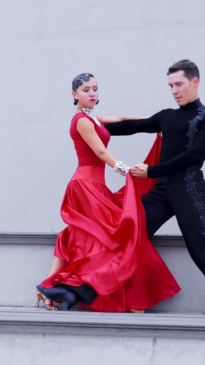 Dancers performing passionate tango in vibrant red costumes against a neutral background