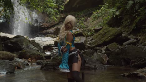 una mariposa pasa volando junto a una cosplayer de anime lucy heartfilia mientras posa en la base de una cascada épica