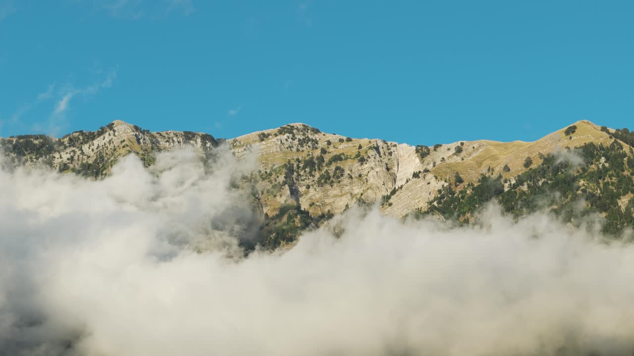 Aerial view of Albanian mountain range and white clouds near foothill
