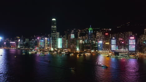 Vista-Aérea-Nocturna-De-Hong-Kong-De-La-Isla-De-Hong-Kong,-Barcos-Navegando-En-El-Puerto-De-Victoria