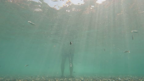 underwater view of fish hook by fisherman fishing on standing at the seashore mediterranean sea