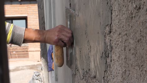 trabajador de la construcción enlucidando la pared usando hormigón