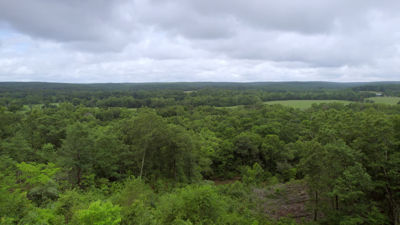 Lento afastamento de um deck sobre árvores e em direção à bela paisagem campestre em um dia de verão nublado no sul do Missouri