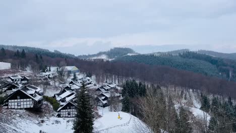 Pan-De-Un-Bosque-De-Invierno-A-Un-Pequeño-Pueblo-Con-Casas-Cubiertas-De-Nieve-En-Invierno