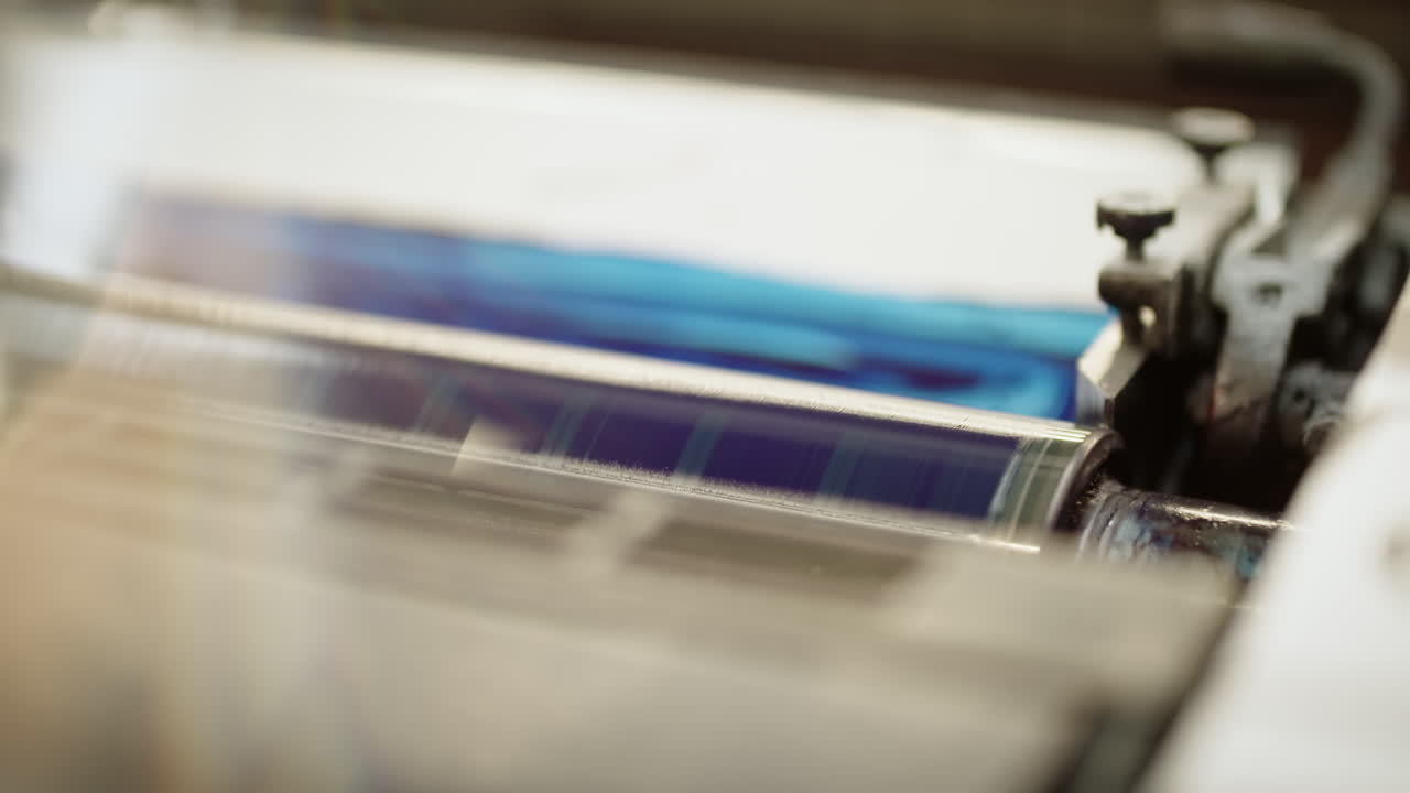 Printing roller turning, covered in ultramarine color, printing on the paper